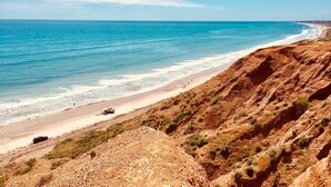 Un paysage côtier avec une plage, des falaises rocheuses et un ciel bleu dégagé.