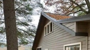 A house with a sloped roof, large windows, and a view of a lake. - Lake St Catherine Cabin For Two with deck and lake access (Poultney)