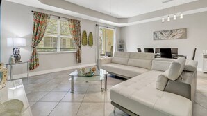 A modern living room with a sectional sofa, a glass coffee table, and a flat-screen TV.