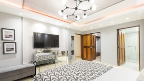 Un dormitorio moderno con una cama grande, un televisor, un banco y un vestidor.
