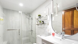 Un baño moderno con cabina de ducha de vidrio, inodoro blanco y tocador con espejo.
