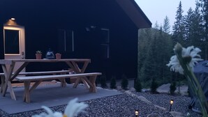 Et moderne hus med en træterrasse, et bord og plantekasser.