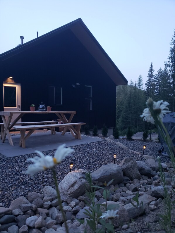 A modern house with a wooden deck, a table, and potted plants.