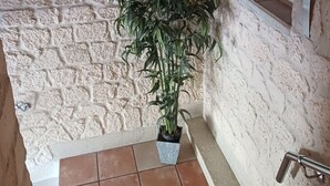 Eine Steinsäule mit einem Blumentopf, einem Feuerelement und einem Metallgeländer.