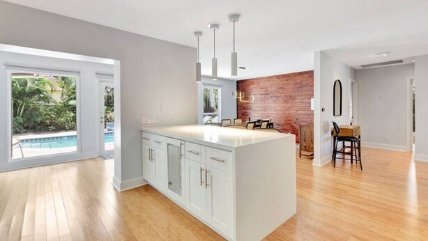 A spacious kitchen with a large island, wooden flooring, and a view of a swimming pool. - Idyllic Boca Pool Home: 4/2.5 + Study-FAU & Mizner (Boca Raton)