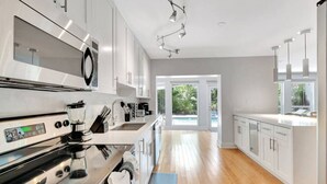A modern kitchen with stainless steel appliances, white cabinetry, and a wooden floor. - Idyllic Boca Pool Home: 4/2.5 + Study-FAU & Mizner (Boca Raton)