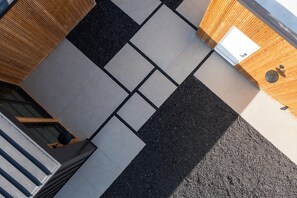 A top-down view of a building's exterior with a mix of tiled and wooden flooring, a staircase, and a door.