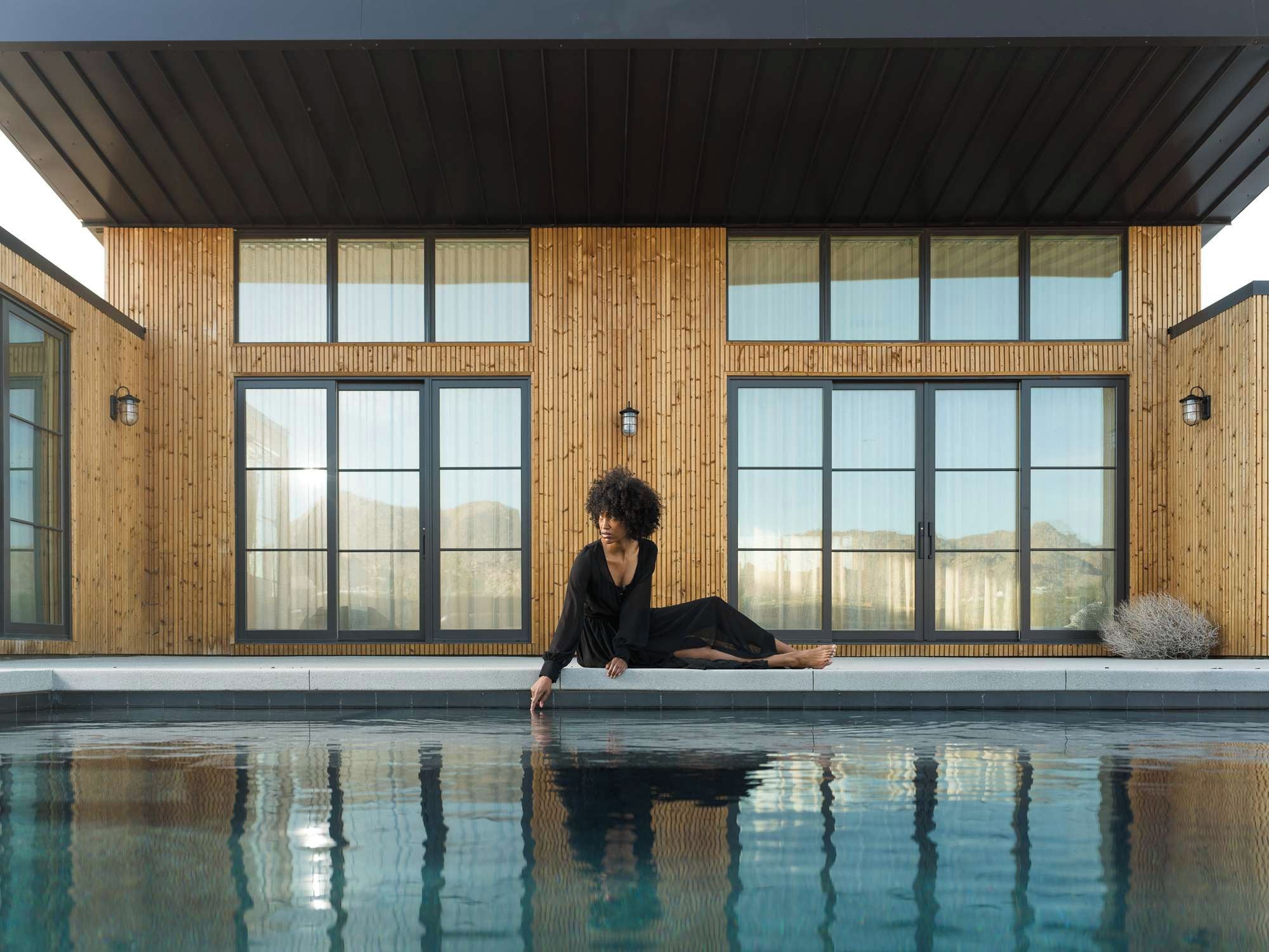 The Lunawood features a striking and functional design element—a large black metal overhang that gracefully extends over the exterior, providing shade and protection to the interior spaces.