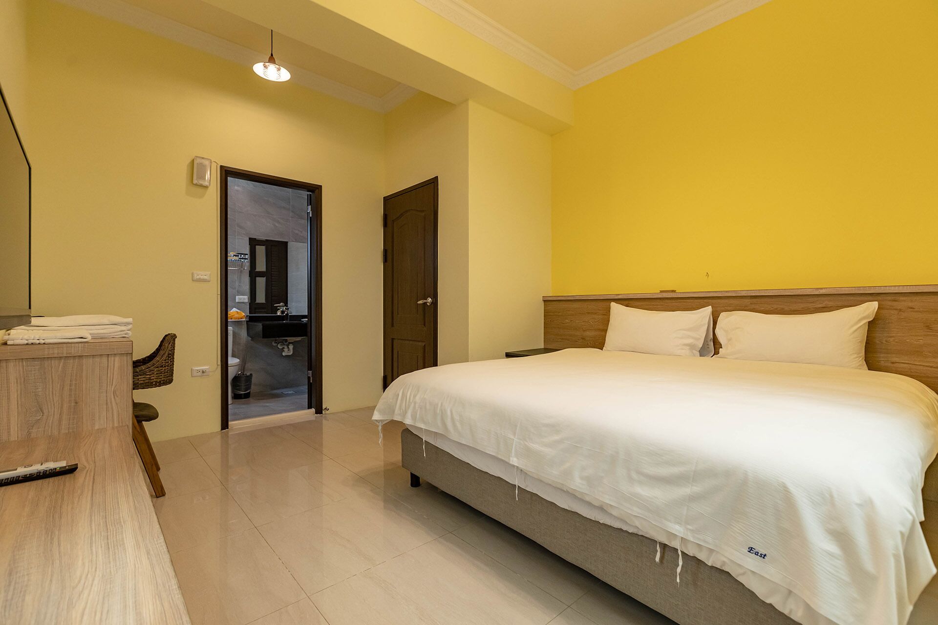 A hotel room with a bed, a desk, a mirror, and a bathroom visible through an open door.