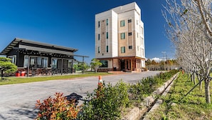 Un edificio moderno con techo plano, una zona de estar al aire libre techada y un camino pavimentado.