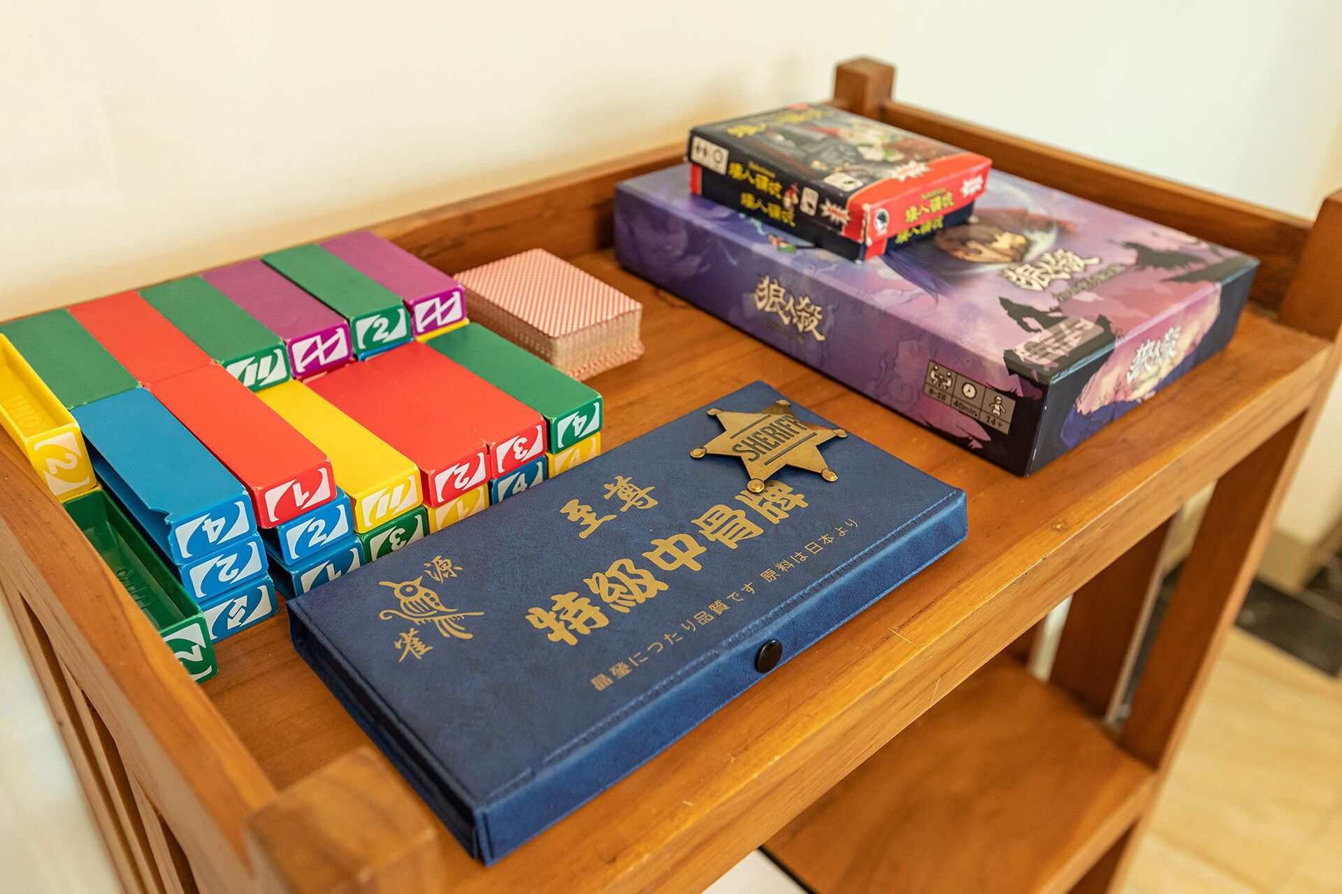 A wooden table with several board games and a blue book with gold lettering.