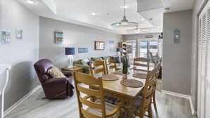 A dining area with a wooden table and chairs, a leather chair, and a ceiling light fixture. - Ozark Overlook – Waterfront, Two Pools, Tennis, and More! (Lake Ozark)