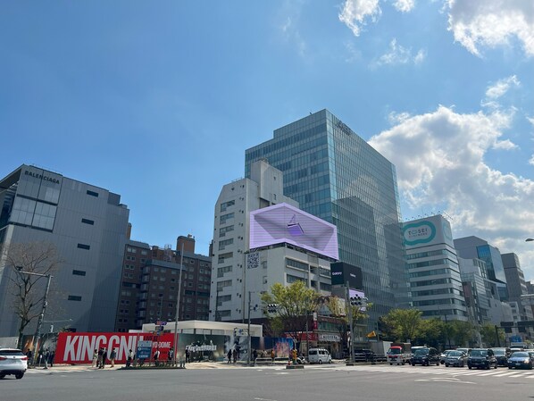 Un paisaje urbano con edificios modernos, que incluye una tienda Balenciaga y un cartel de Galaxy.
