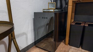 A compact kitchen with a modern design, featuring a black refrigerator, a coffee maker, and a kettle on the countertop. - INN THE OMOTESANDO (Tokyo)