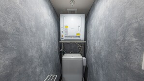 A compact, narrow bathroom with a toilet and a small sink. - INN THE OMOTESANDO (Tokyo)