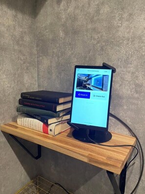 Un monitor de computadora sobre una repisa de madera, con una pila de libros a un lado.