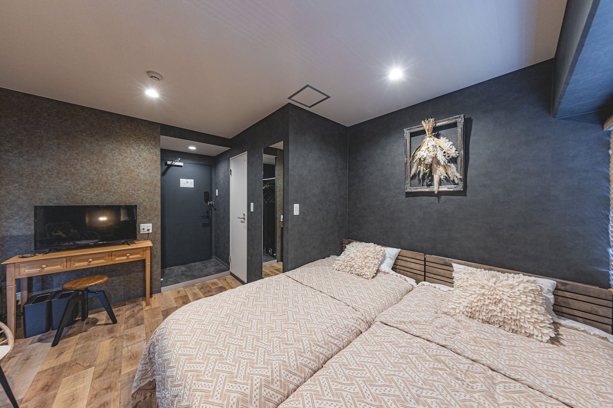 A bedroom with a large bed, a desk, and a television.