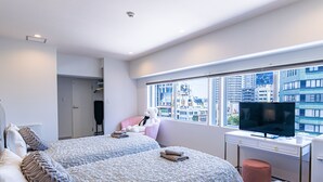A modern hotel room with two beds, a television, and a large window offering a city view. - INN THE OMOTESANDO (Tokyo)