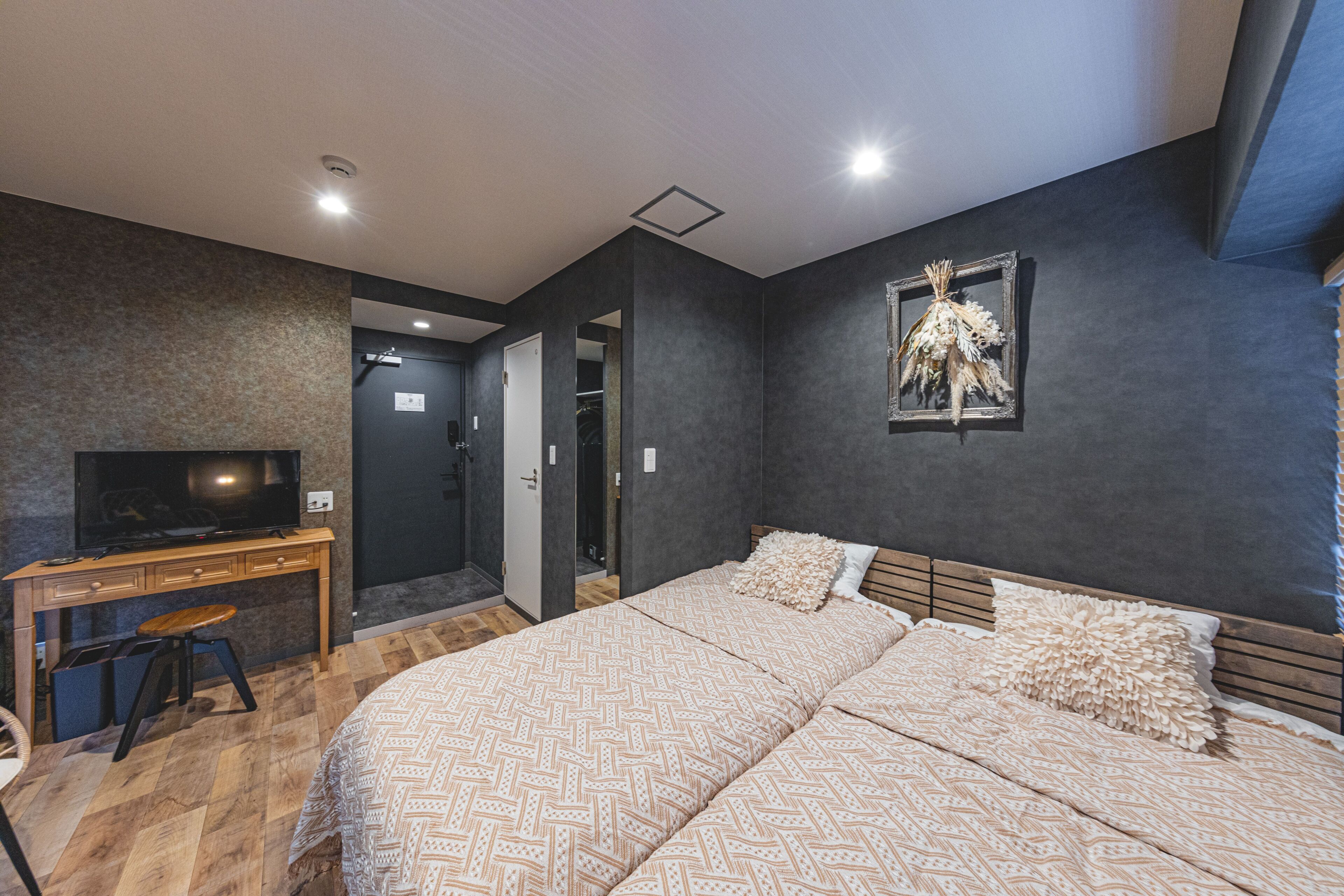 A bedroom with a bed, a desk, a television, and a door leading to a bathroom.