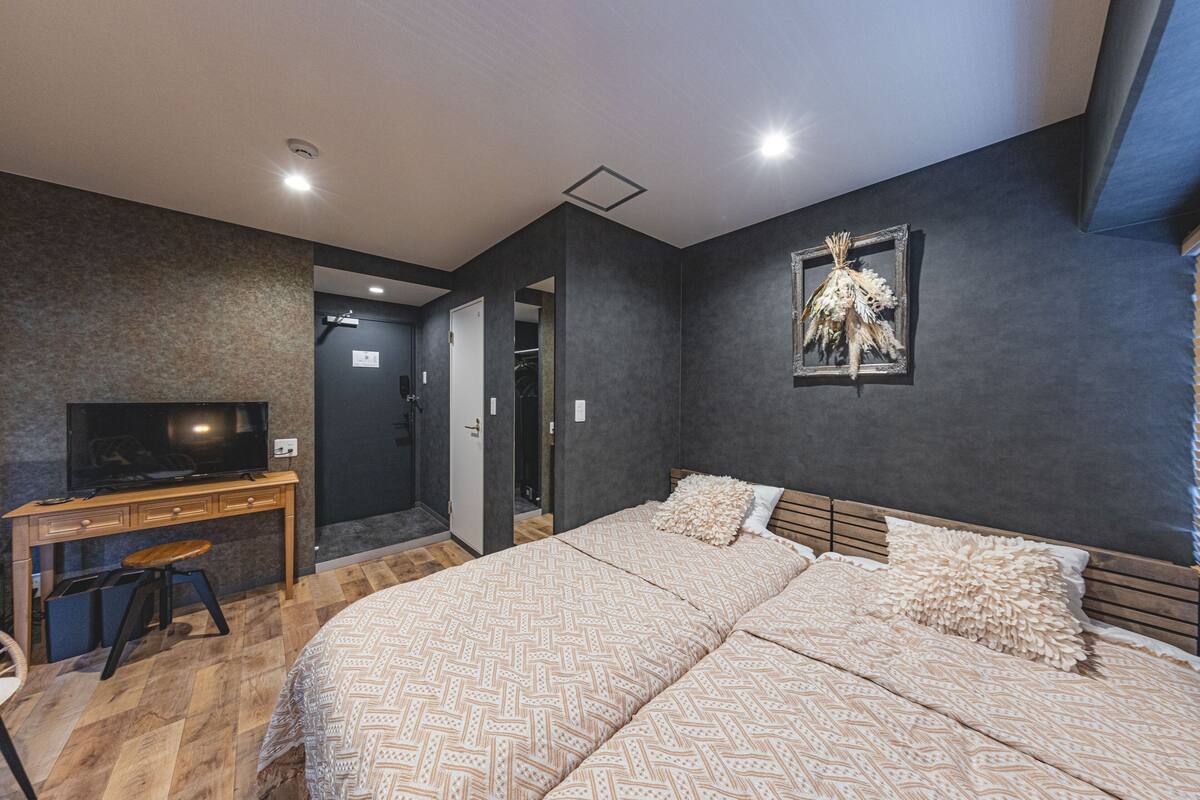 A bedroom with a bed, a desk, a television, and a door leading to a bathroom.