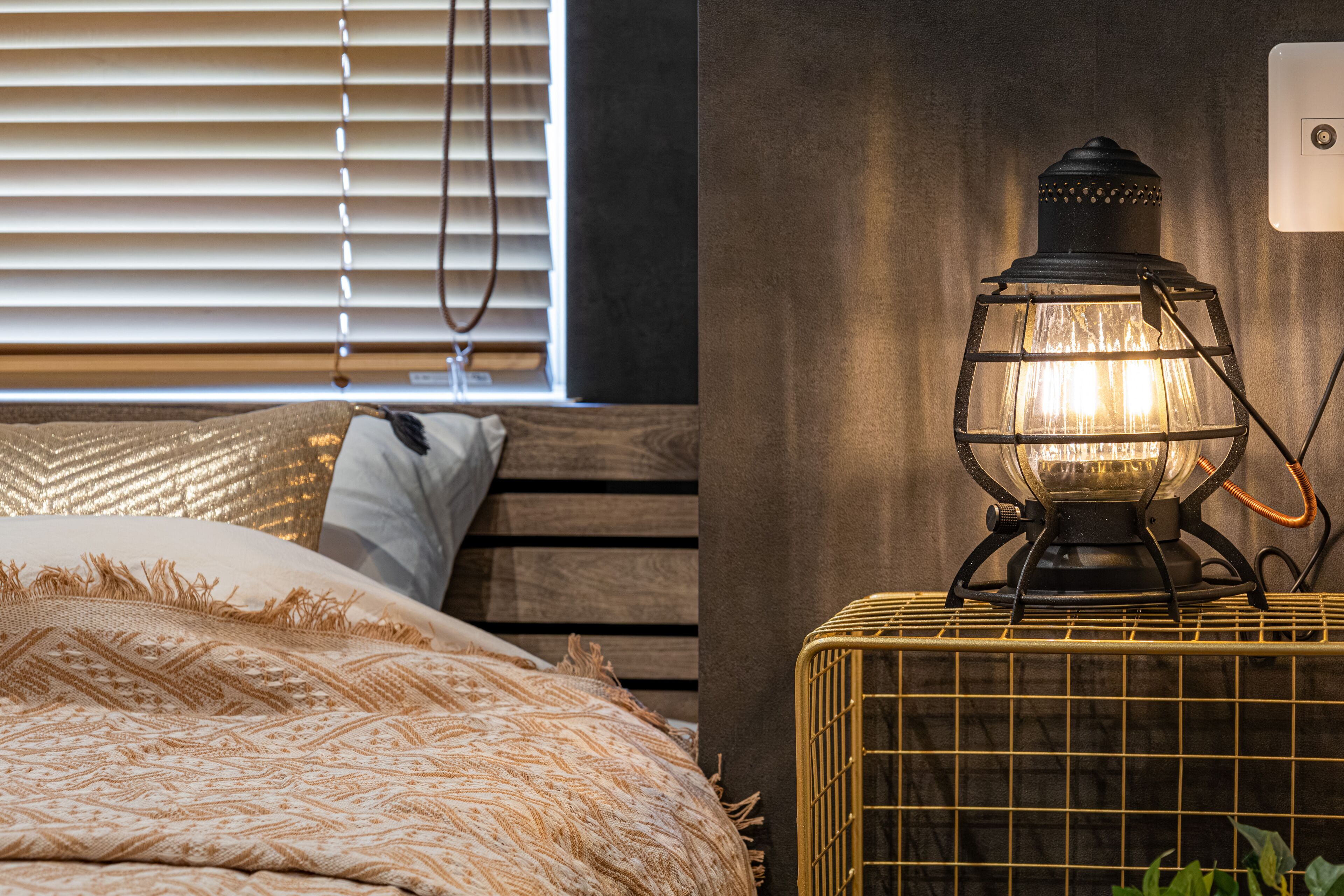 A bed with patterned bedding and a bedside lamp on a nightstand.