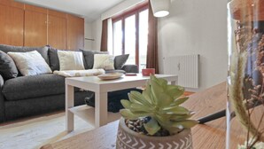 Un salon avec un canapé gris, une table basse blanche et une plante en pot.
