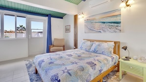 Una camera da letto con un letto, una sedia, un comodino, un quadro e vista sull'esterno.