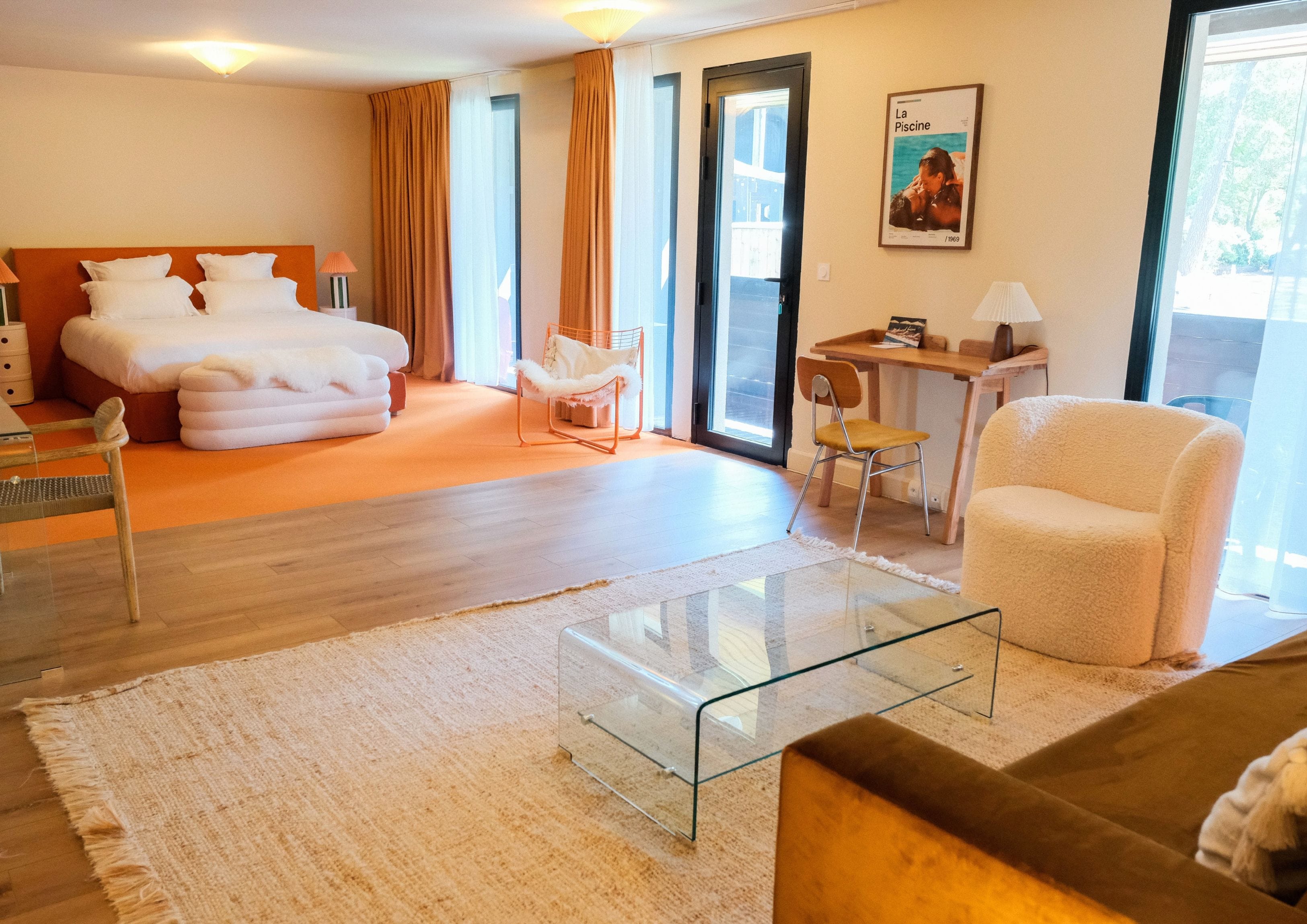 Ein Hotelzimmer mit einem Bett, einem Glastisch, einer Couch, einem Sessel und einem Schreibtisch mit einer Lampe.