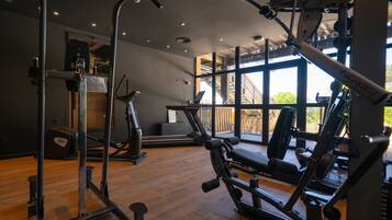 A gym with cardio machines, weightlifting equipment, and a large window providing natural light.
