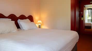 Ein Hotelzimmer mit einem großen Bett, einem Nachttisch mit Lampe und einer Tür, die auf einen Balkon führt.