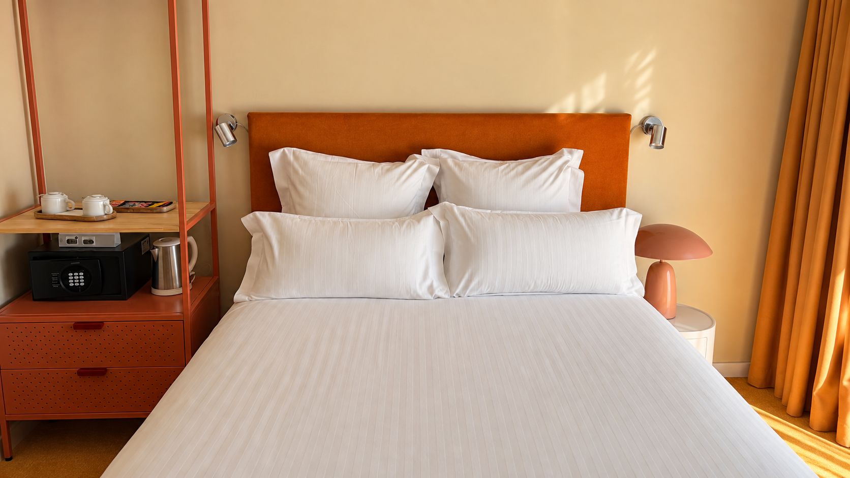 A hotel room with a bed, a nightstand, a lamp, and a minibar.