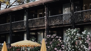 Zona junto a la piscina con sillones de descanso y sombrillas, una piscina y un edificio con balcones.