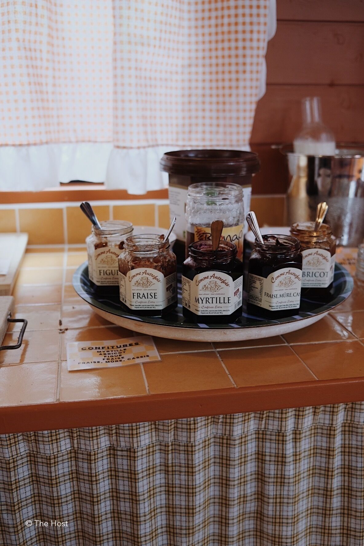 Una bandeja con frascos etiquetados con nombres como 'FRAISE' y 'MYRTILLE' sobre una encimera de cocina.