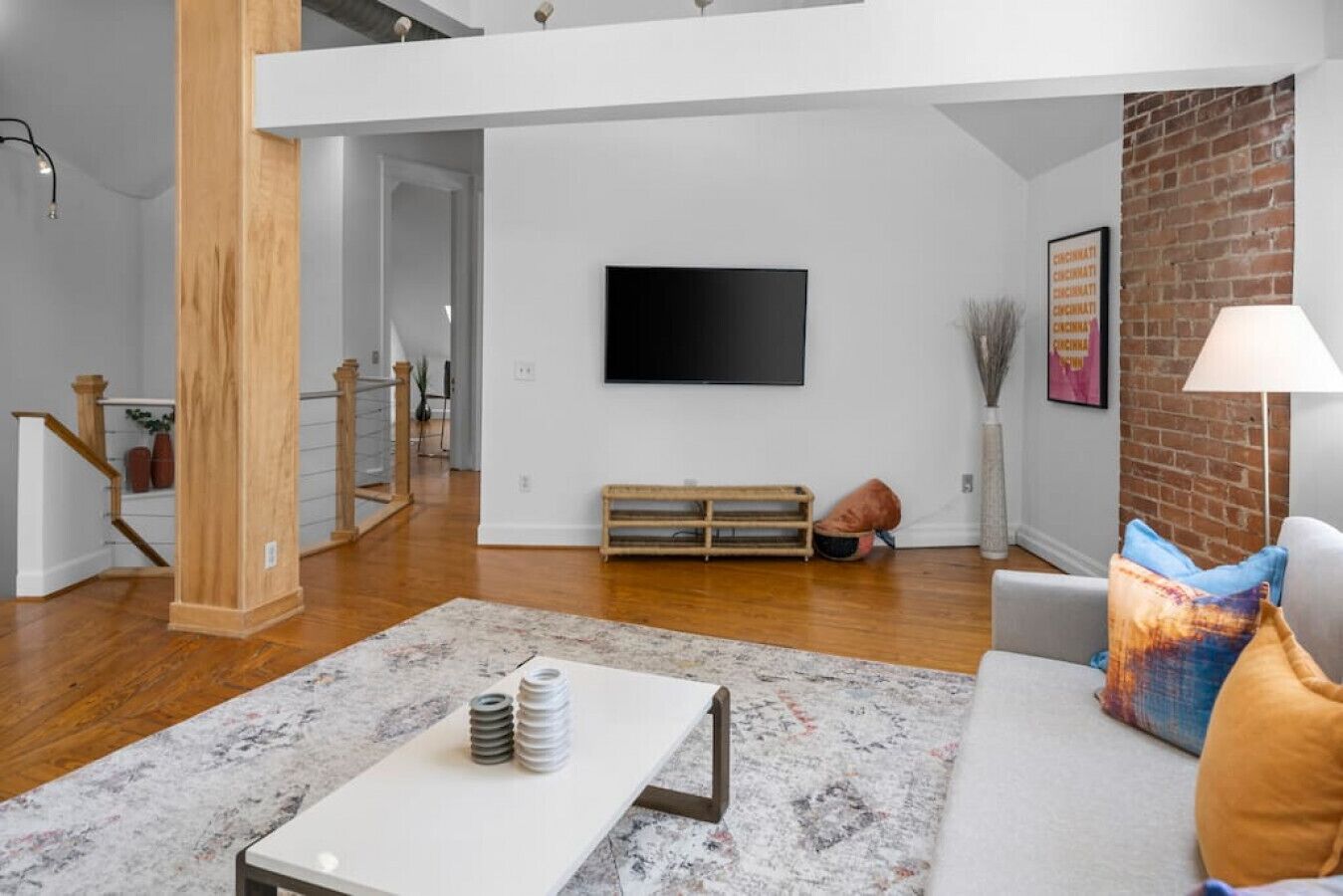 Un salon moderne avec un téléviseur à écran plat, un canapé gris et une table basse.