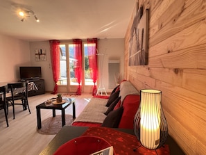Uma sala de estar com sofá, mesa de centro, televisão e abajur.