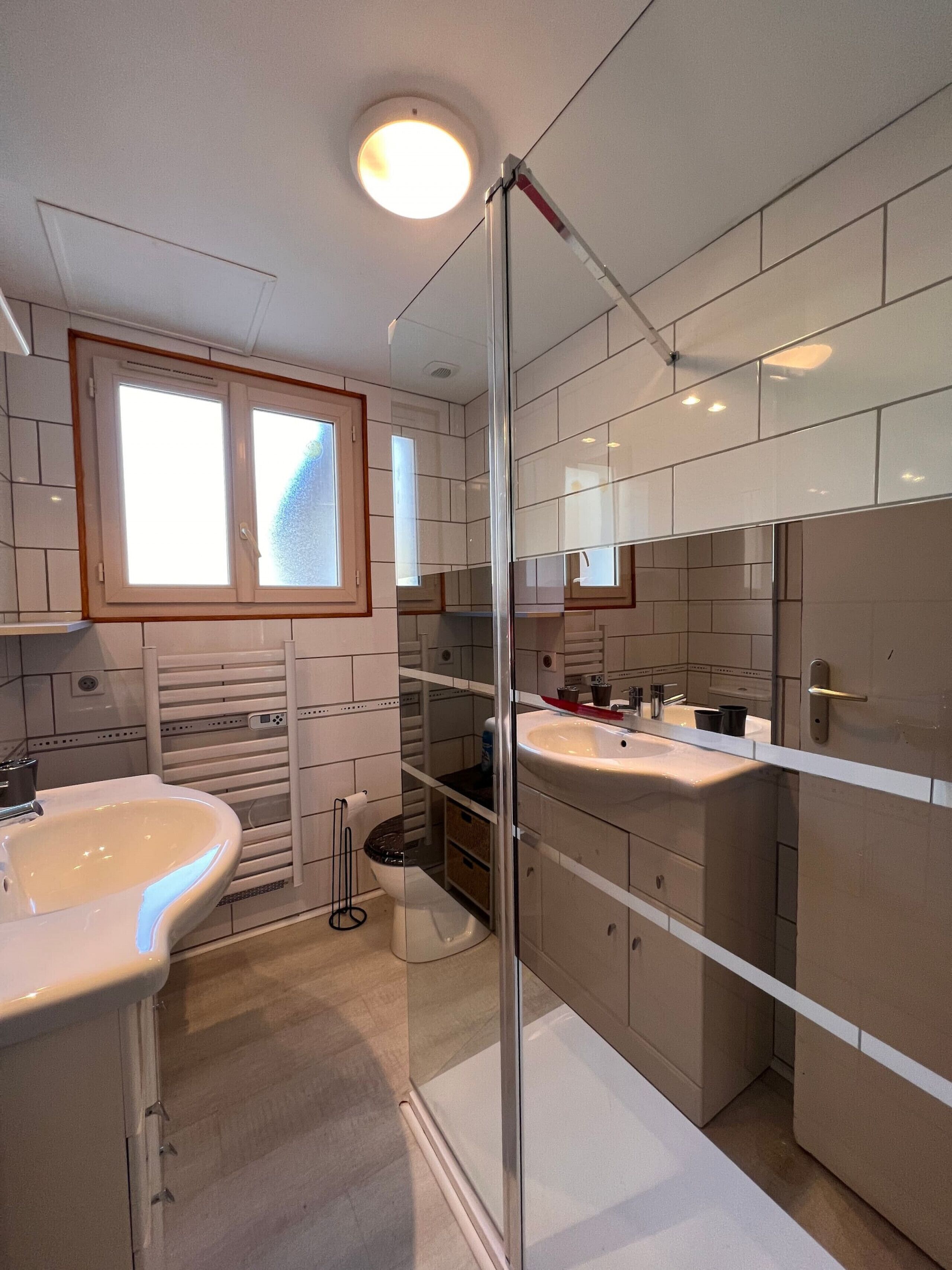 Un baño moderno con dos lavamanos, cabina de ducha de vidrio y un espejo grande.