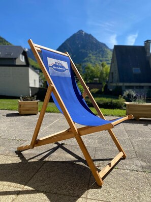 A blue beach chair with a logo on the backrest, placed on a paved surface outdoors. - T2 ensoleillé avec terrasse et vaste jardin commun (Cauterets)
