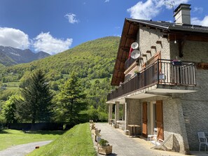 A mountain lodge with outdoor seating and a view of the surrounding forest and mountains.