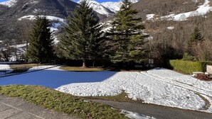Eine Berglandschaft mit schneebedeckten Gipfeln, blauem Himmel und einem kleinen Teich mit Eis.