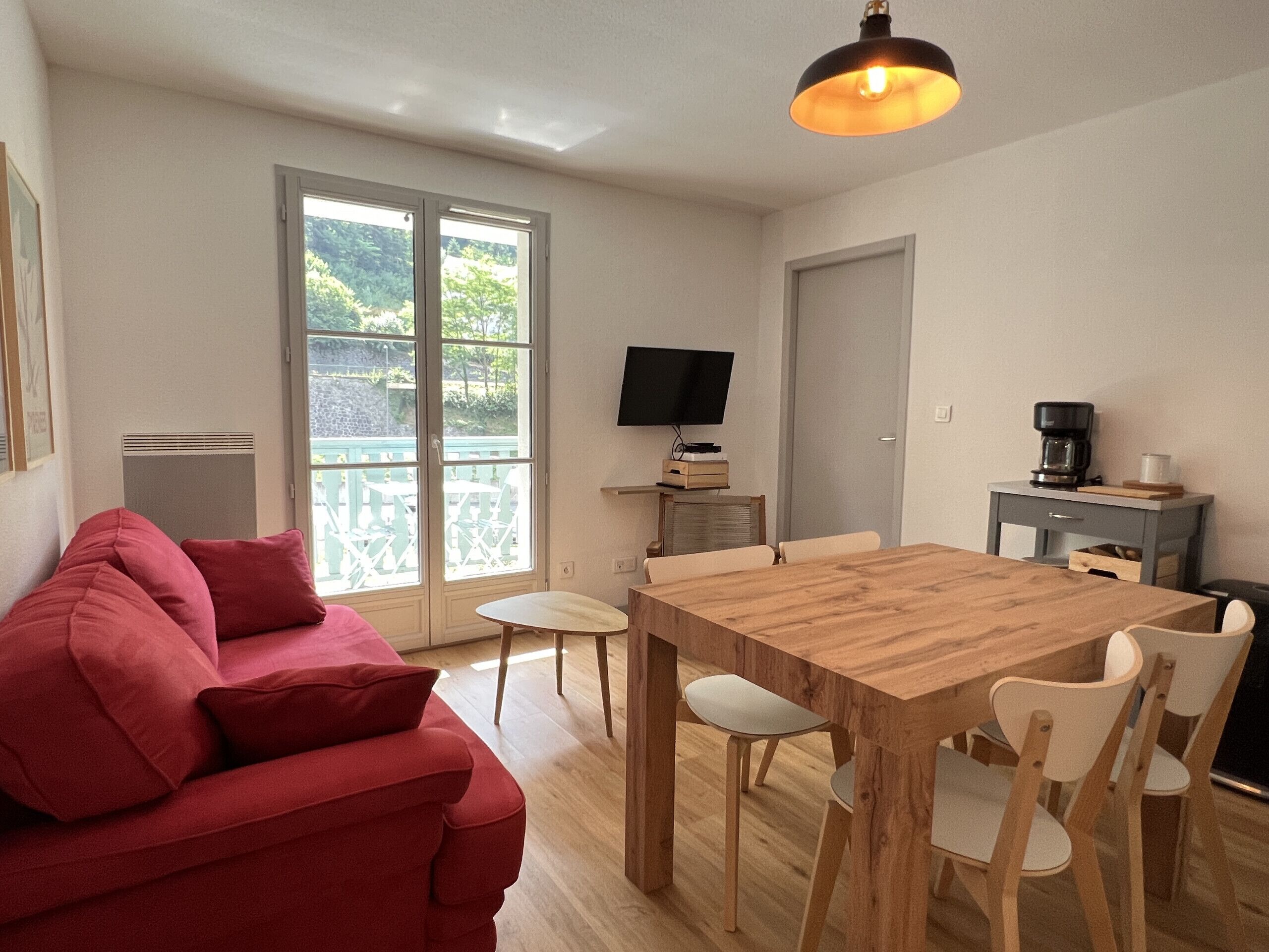 Un espacio habitable moderno con sofá, mesa de comedor, sillas, televisor y cafetera.