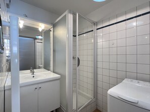 A bathroom with a glass-enclosed shower, a sink, and a mirror. - T3 centre ville avec parking, balcon et wifi. 5P. (Cauterets)