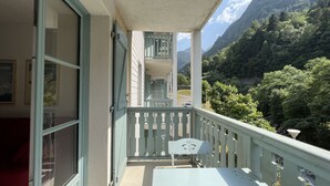 Un balcón con mesa y sillas, con vistas a un paisaje montañoso de exuberante vegetación.