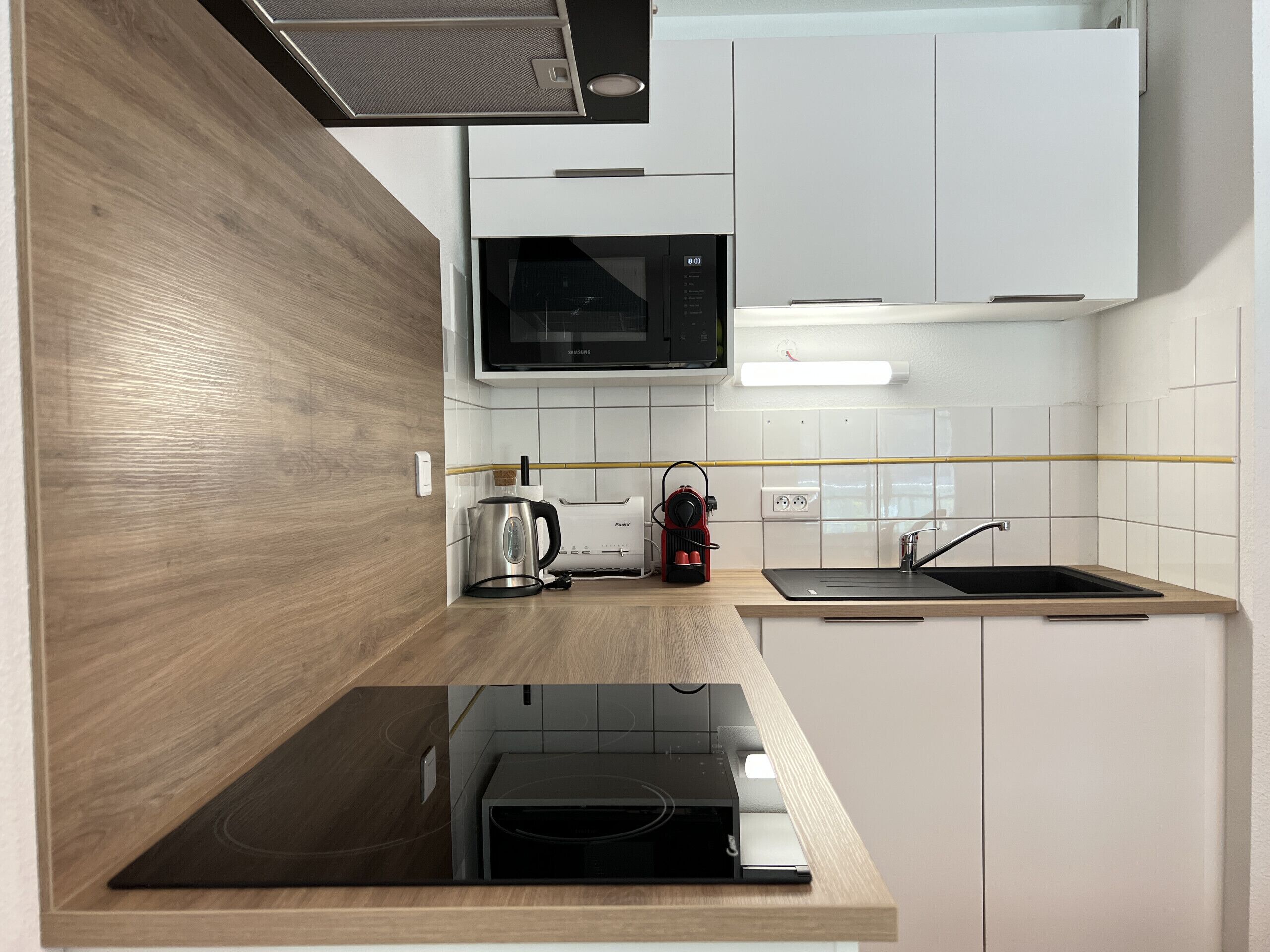 A modern kitchen with a microwave, kettle, and induction cooktop.