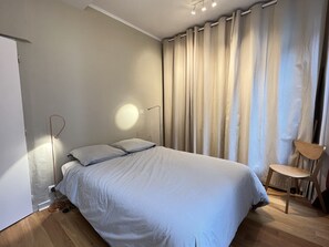 Een slaapkamer met een bed, een stoel en een vloerlamp.