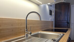 A modern kitchen with stainless steel appliances, a wooden countertop, and a built-in oven. - Charmant T3 - Cœur de Cauterets (Cauterets)