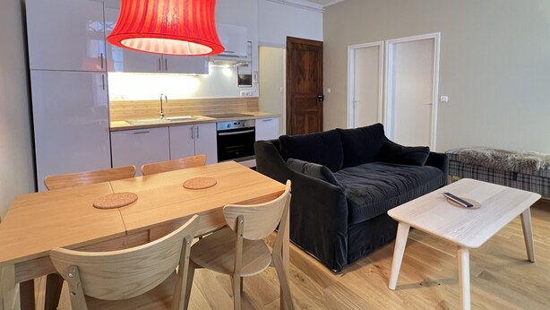 A compact living space with a dining area, a sofa, and a small table. - Charmant T3 - Cœur de Cauterets (Cauterets)