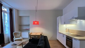 A modern living room with a black sofa, a wooden coffee table, and a red pendant light. - Charmant T3 - Cœur de Cauterets (Cauterets)