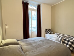 A room with a bed, a bedside table, and a window with curtains. - Charmant T3 - Cœur de Cauterets (Cauterets)