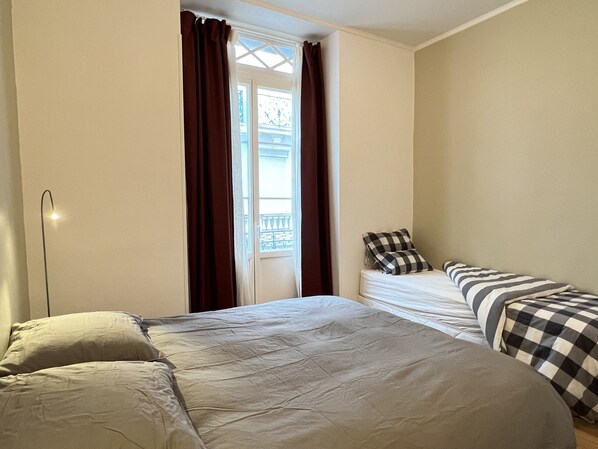A room with a bed, a bedside table, and a window with curtains.