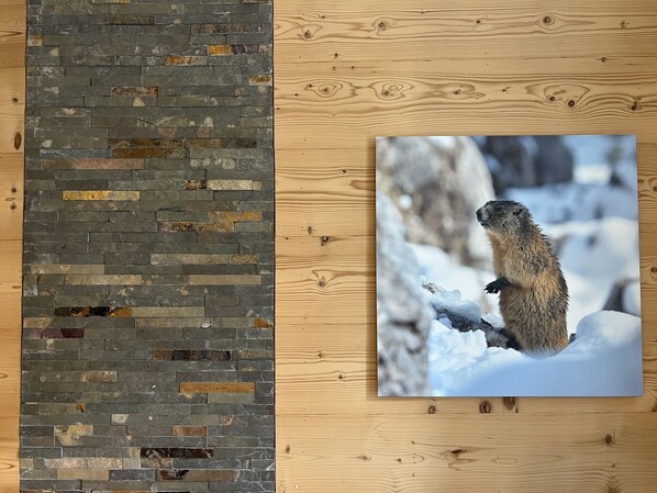 Una pared con un diseño de mosaico de piedra y una fotografía enmarcada de una marmota en un paisaje nevado.